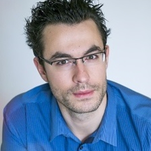 Dark-haired person with glasses and blue shirt