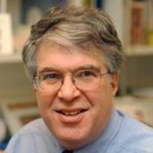Smiling person with brown hair and glasses