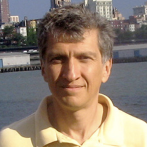 Person smiling with closed mouth in front of a harbor skyline