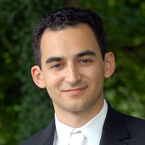 Smiling person in business suit in front of foliage