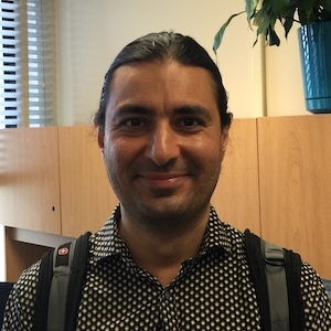 Smiling person with combed-back hair in an office cubicle