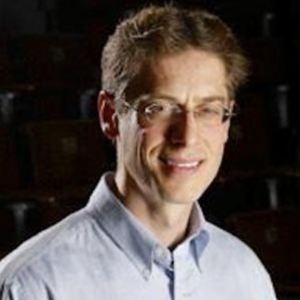 Smiling person with short brown hair and glasses