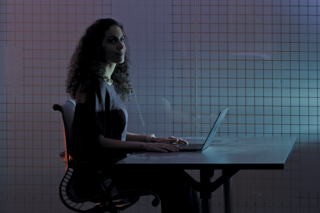 Person with long curly hair at a laptop